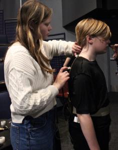 photo of a student sound crew member putting a mic on a student actor