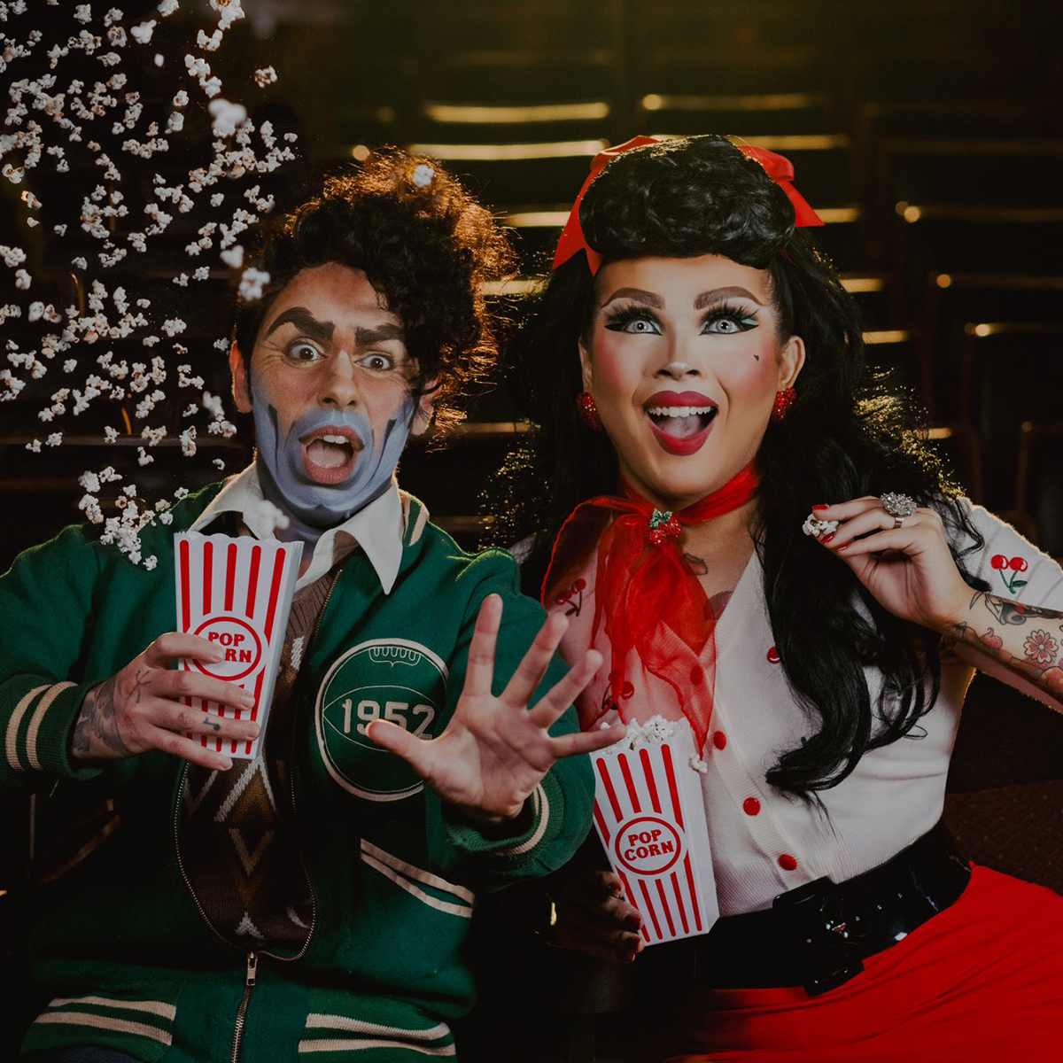 Briar and Rusty in a movie theater holding popcorn, Briar on the right looks engaged and happy, Rusty on the left is surprised as popcorn flys in the air
