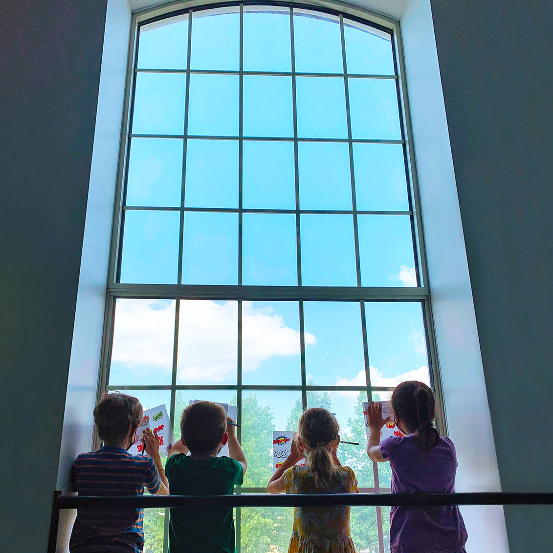 4 youth students drawing against a large window in the Mosesian Arts teaching studio