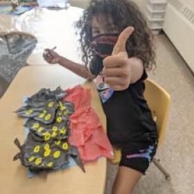 K2 student gives "thumbs up" to the camera while working on an art project