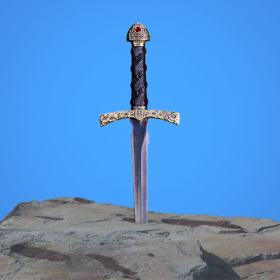 an ornate dagger sticking into a stone with a blue sky in the background
