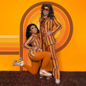 Performers Briar and Rusty pose in orange and brown striped outfits against an orange and brown striped background