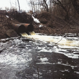 2 large pipes dump polluted water into a river
