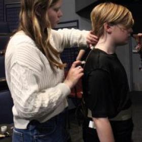 photo of a student sound crew member putting a mic on a student actor